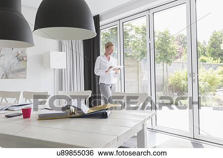 Mature woman working with mobile devices in modern living room View Large Photo Image Stock Photograph - Mature woman working with mobile devices in modern living room. Fotosearch