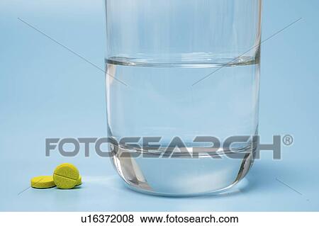 Stock Photo - Medication and glass of water on a blue background.. Fotosearch