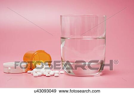 Stock Photo - Medication and glass of water on a red background.. Fotosearch