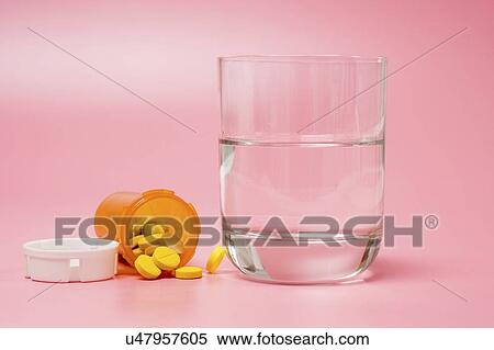 Stock Photography - Medication and glass of water on a red background.. Fotosearch