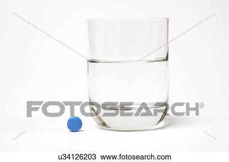 Stock Image - Medication and glass of water on a white background.. Fotosearch