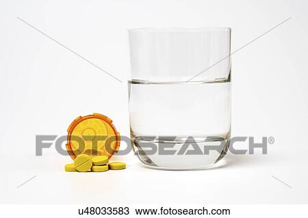 Stock Image - Medication and glass of water on a white background.. Fotosearch