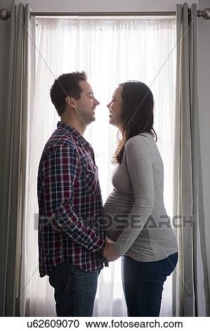 Mid adult couple in front of window, laughing View Large Photo Image Stock Image - Mid adult couple in front of window, laughing. Fotosearch