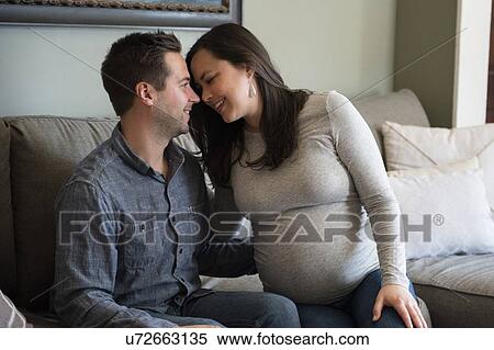Stock Photography - Mid adult couple sitting on sofa. Fotosearch