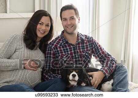 Mid adult couple sitting on sofa with puppy View Large Photo Image Stock Image - Mid adult couple sitting on sofa with puppy. Fotosearch