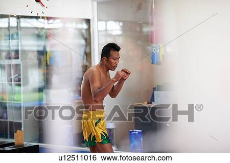 Stock Photograph - Mid adult male boxer practicing in gym. Fotosearch