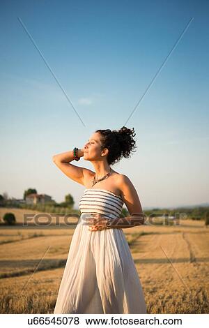 Mid adult woman, standing in field, enjoying sunshine View Large Photo Image Stock Photo - Mid adult woman, standing in field, enjoying sunshine. Fotosearch