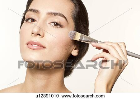 MODEL RELEASED. Young woman applying foundation to cheek with make up brush. View Large Photo Image Stock Image - MODEL RELEASED. Young woman applying foundation to cheek with make up brush.. Fotosearch