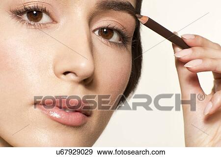 MODEL RELEASED. Young woman applying eyebrow pencil. View Large Photo Image Stock Photo - MODEL RELEASED. Young woman applying eyebrow pencil.. Fotosearch
