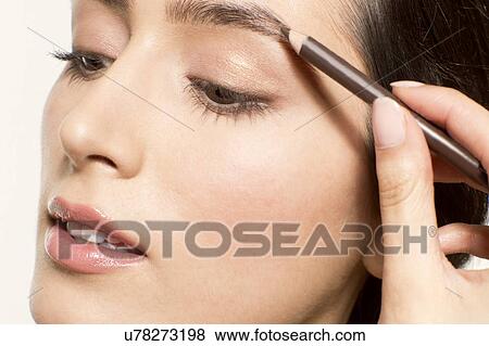 Stock Photo - MODEL RELEASED. Young woman applying eyebrow pencil.. Fotosearch