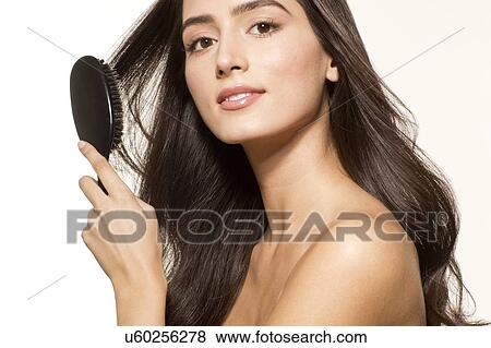 MODEL RELEASED. Young woman brushing long brown hair, portrait. View Large Photo Image Stock Photo - MODEL RELEASED. Young woman brushing long brown hair, portrait.. Fotosearch