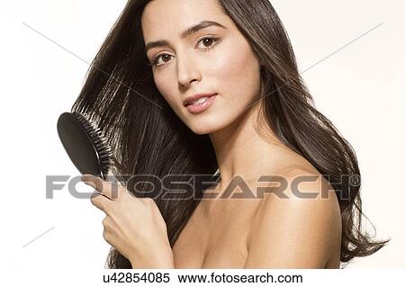 Stock Photography - MODEL RELEASED. Young woman brushing long brown hair, portrait.. Fotosearch