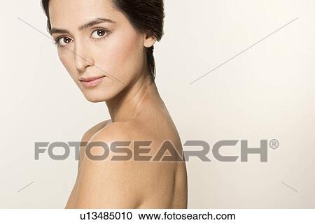Stock Image - MODEL RELEASED. Young woman looking at camera, side portrait.. Fotosearch