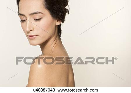 Stock Image - MODEL RELEASED. Young woman looking down, side portrait.. Fotosearch