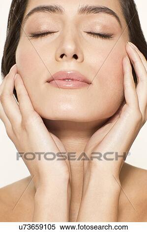 Stock Photography - MODEL RELEASED. Young woman touching face with eyes closed, portrait.. Fotosearch