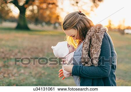 Mother and baby daughter outdoors, mother carrying baby in baby sling View Large Photo Image Stock Image - Mother and baby daughter outdoors, mother carrying baby in baby sling. Fotosearch