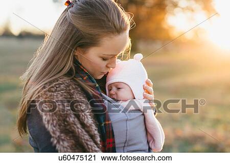 Stock Image - Mother and baby daughter outdoors, mother carrying baby in baby sling. Fotosearch