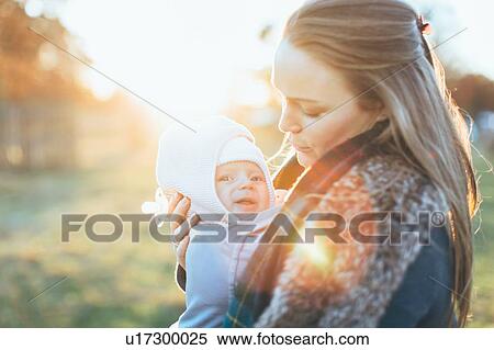 Stock Photography - Mother and baby daughter outdoors, mother carrying baby in baby sling. Fotosearch