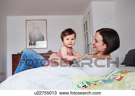 Mother and baby daughter relaxing on bed View Large Photo Image Stock Image - Mother and baby daughter relaxing on bed. Fotosearch