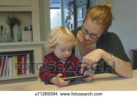 Mother and son (2-3) playing on smart phone View Large Photo Image Picture - Mother and son (2-3) playing on smart phone. Fotosearch