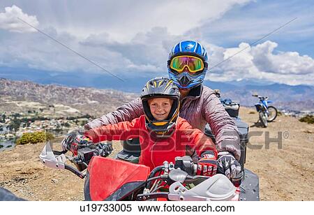 Stock Photography - Mother and son on top of mountain, using quad bike, La Paz, Bolivia, South America. Fotosearch