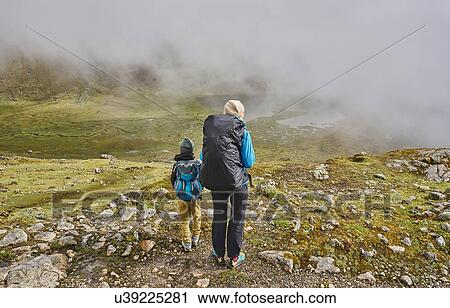 Stock Image - Mother and son, trekking through landscape, rear view, Ventilla, La Paz, Bolivia, South America. Fotosearch