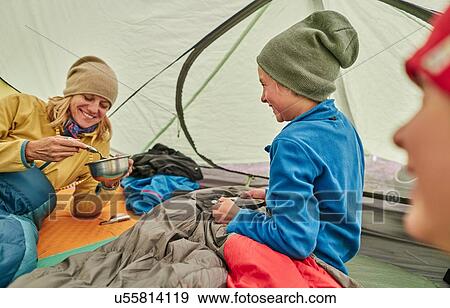 Stock Photo - Mother and sons in tent, eating food from bowls, Ventilla, La Paz, Bolivia, South America. Fotosearch