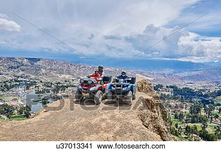 Stock Image - Mother and sons on top of mountain, using quad bikes, La Paz, Bolivia, South America. Fotosearch