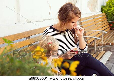 Mother and toddler daughter eating ice cream on park bench View Large Photo Image Stock Image - Mother and toddler daughter eating ice cream on park bench. Fotosearch