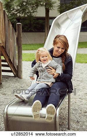 Picture - Mother and toddler daughter on playground slide. Fotosearch