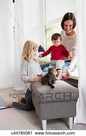 Mother and two daughters playing with pet cat View Large Photo Image Stock Image - Mother and two daughters playing with pet cat. Fotosearch