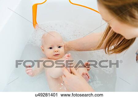 Stock Image - Mother bathing baby daughter. Fotosearch