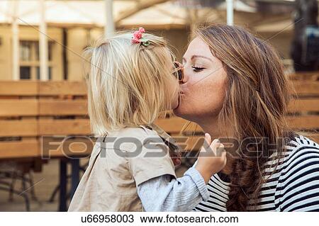 Mother kissing toddler daughter on park bench View Large Photo Image Stock Image - Mother kissing toddler daughter on park bench. Fotosearch