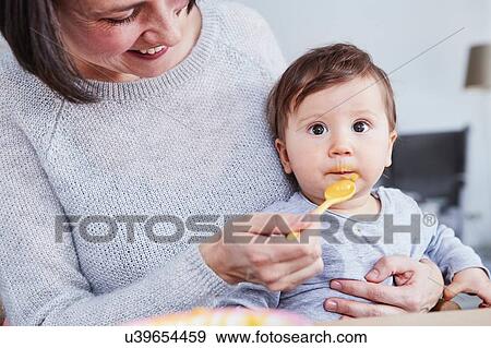 Mother spoon-feeding baby daughter View Large Photo Image Stock Photo - Mother spoon-feeding baby daughter. Fotosearch