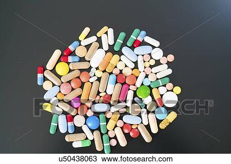 Stock Image - Multicolored pills and capsules on a black background.. Fotosearch