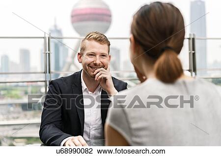Over shoulder view of young businessman and woman having meeting at sidewalk cafe in Shanghai financial centre, Shanghai, China View Large Photo Image Stock Image - Over shoulder view of young businessman and woman having meeting at sidewalk cafe in Shanghai financial centre, Shanghai, China. Fotosearch