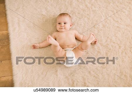 Overhead portrait of cute baby girl in diaper lying on beige rug View Large Photo Image Stock Photo - Overhead portrait of cute baby girl in diaper lying on beige rug. Fotosearch