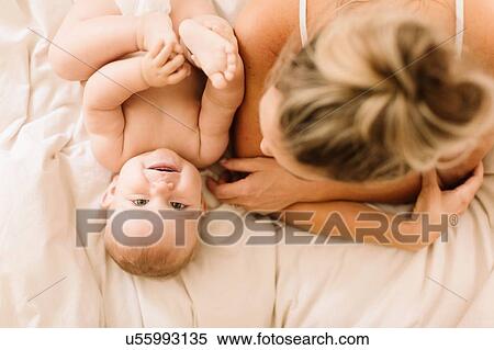 Overhead portrait of cute baby girl lying on bed with mother View Large Photo Image Stock Photography - Overhead portrait of cute baby girl lying on bed with mother. Fotosearch