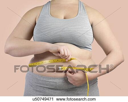 Overweight woman measuring her waist with a tape measure. View Large Photo Image Stock Image - Overweight woman measuring her waist with a tape measure.. Fotosearch