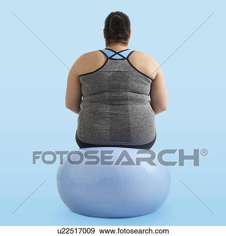 Stock Photo - Overweight woman sitting on an exercise ball, rear view.. Fotosearch