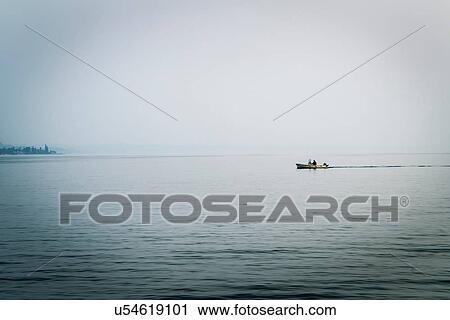 Stock Image - People in distant boat on Lake Garda, Lazise, Veneto, Italy, Europe. Fotosearch