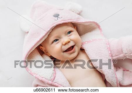 Stock Image - Portrait of baby girl in hooded towel looking away smiling. Fotosearch
