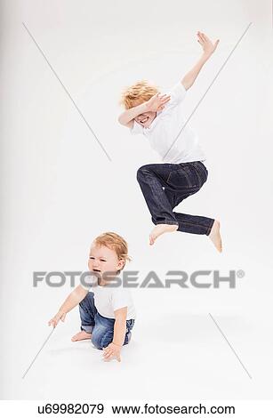 Portrait of boy leaping in air over baby brother View Large Photo Image Stock Photo - Portrait of boy leaping in air over baby brother. Fotosearch