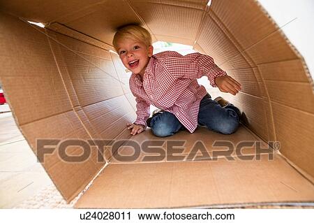 Stock Image - Portrait of boy playing in cardboard box. Fotosearch