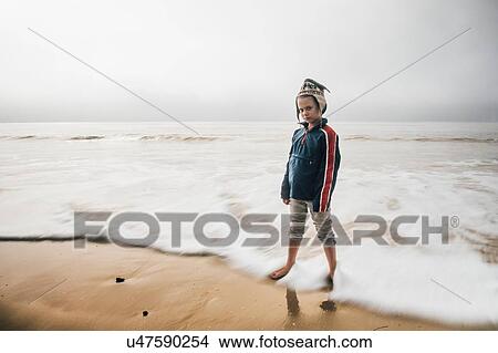 Portrait of boy standing on beach, pensive expression View Large Photo Image Picture - Portrait of boy standing on beach, pensive expression. Fotosearch