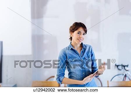 Stock Image - Portrait of businesswoman holding digital tablet, smiling. Fotosearch