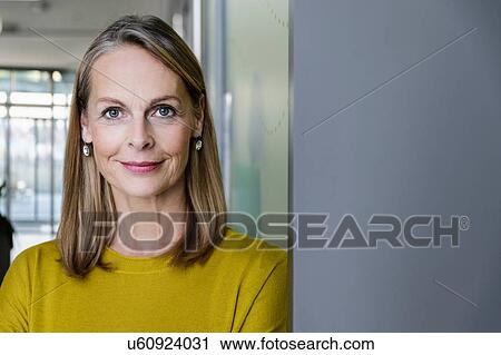 Stock Image - Portrait of confident mature businesswoman in office corridor, head and shoulders. Fotosearch
