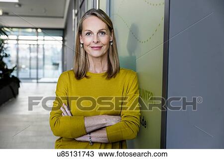 Stock Image - Portrait of confident mature businesswoman in office corridor. Fotosearch
