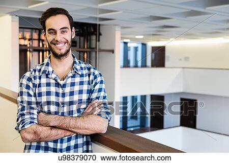 Stock Image - Portrait of confident young businessman in office atrium. Fotosearch