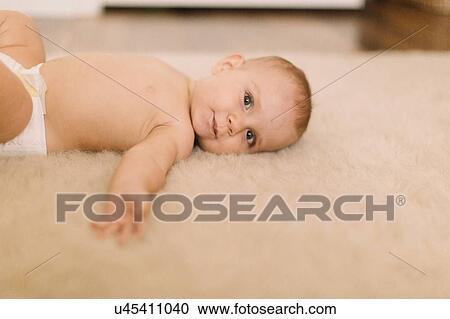 Portrait of cute baby girl in diaper lying on beige rug View Large Photo Image Stock Image - Portrait of cute baby girl in diaper lying on beige rug. Fotosearch